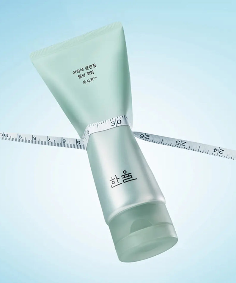 HANYUL Young Artemisia Cleansing Pack Balm 100g, tube vert sur fond bleu, ruban à mesurer visible.