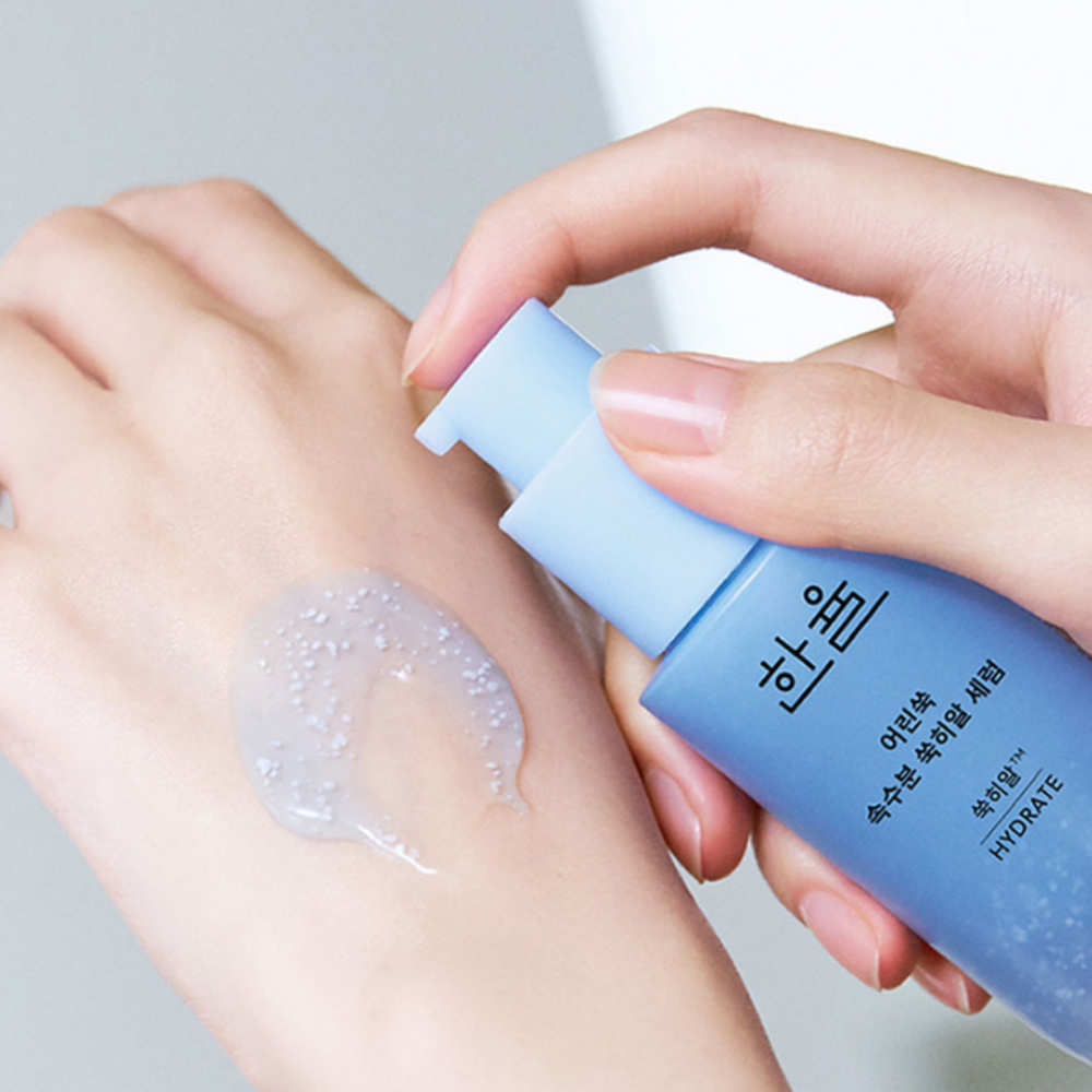 HANYUL Young Artemisia Extract Moisturizing Serum 40ml, application sur peau avec tube bleu, mains et texture crème, fond clair.