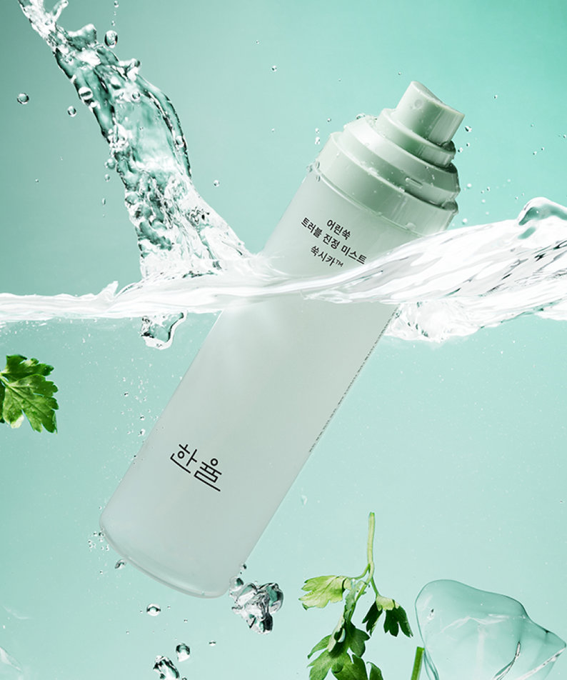 HANYUL Young Artemisia Trouble Mist 120ml de HANYUL, flacon éclaboussé d’eau sur fond turquoise, style spa beauté.