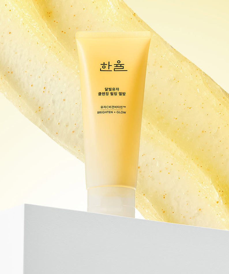 HANYUL Yuja Brightening Peeling Gel Balm Cleanser 100g, tube jaune sur fond blanc, style cosmétique, éclats d’agrumes.