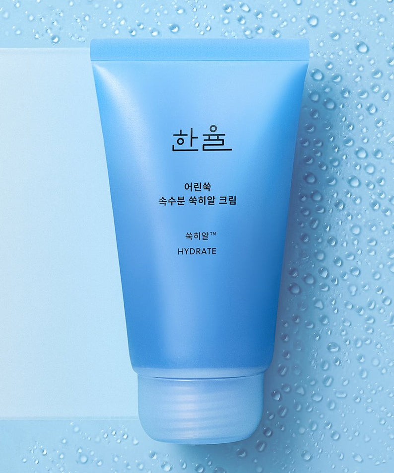 Crème hydratante HANYUL Young Artemisia Extract 60ml sur fond bleu avec gouttes d'eau.
