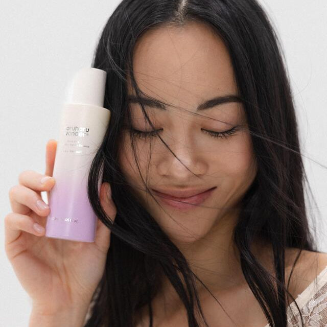 HARUHARU Black Rice Probiotics Barrier Essence 120ml, flacon tenu par une femme, contexte skincare sur fond clair.