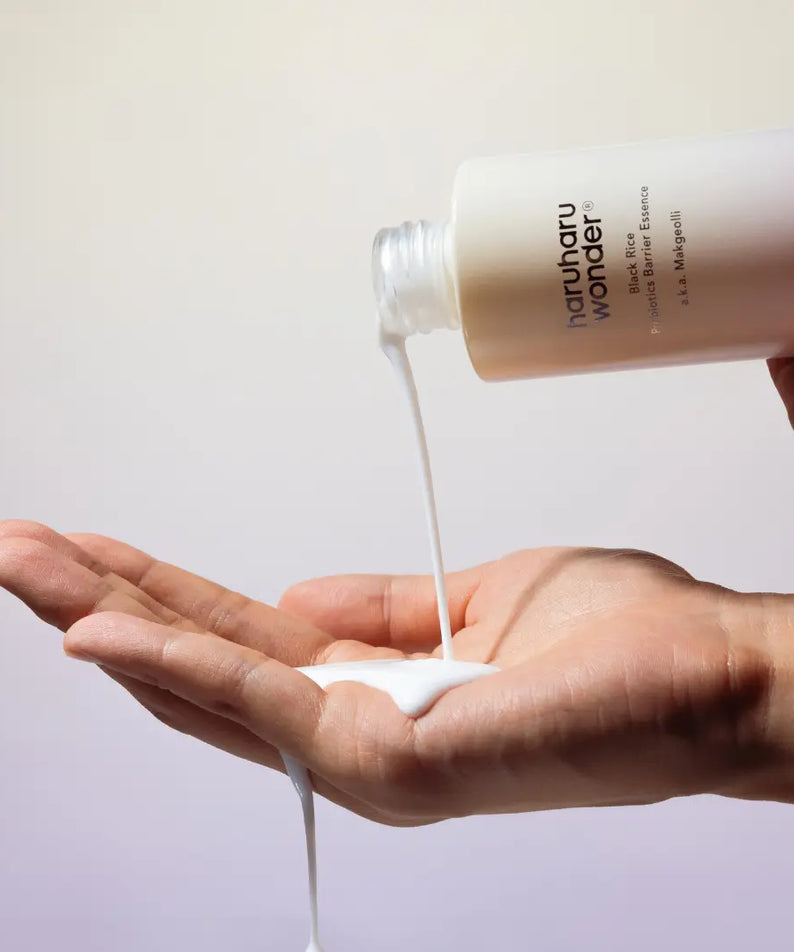 HARUHARU Black Rice Probiotics Barrier Essence 120ml : main recevant le sérum, flacon HARUHARU, fond clair.