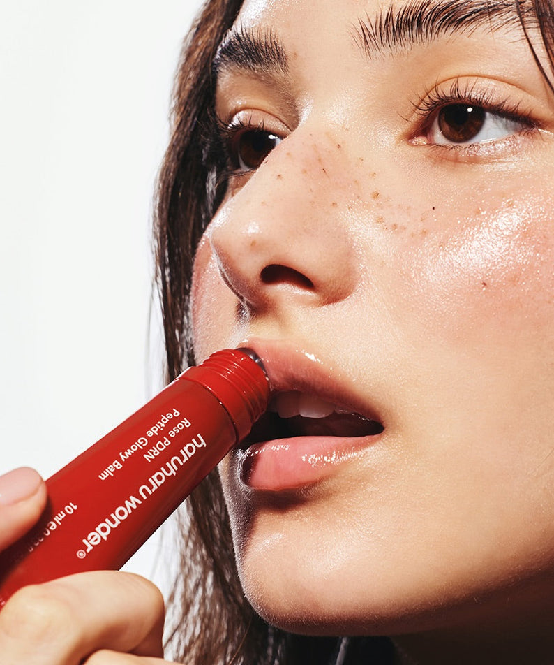 HARUHARU Rose PDRN  Peptide Glowy Balm 10ml, femme appliquant un baume rosé, emballage rouge, peau lumineuse.