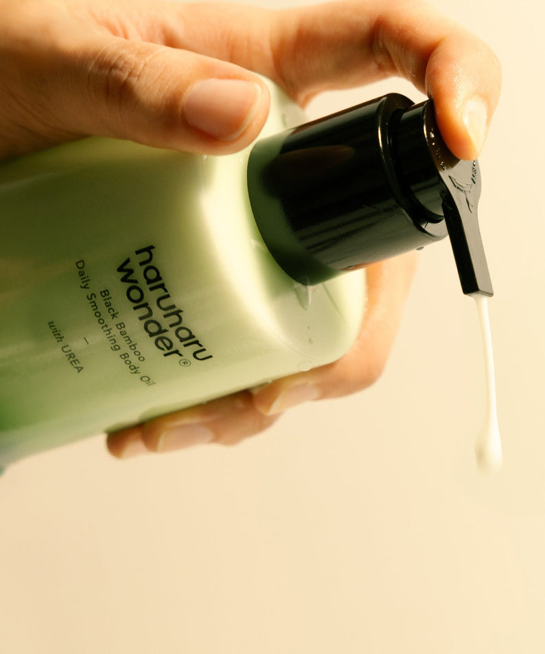 Hands appliquant HARUHARU Black Bamboo Daily Smoothing Body Oil 200ml sur la peau.