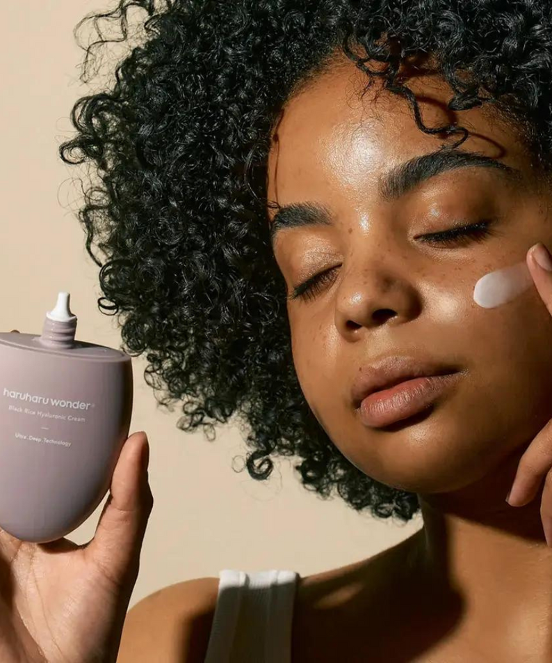 Femme appliquant HARUHARU Black Rice 10 Hyaluronic Cream 50ml sur sa peau, bienfaits hydratants visibles.