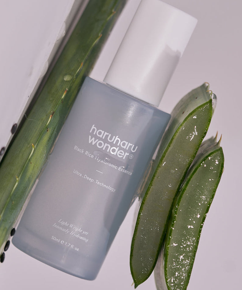 Flacon de HARU HARU Black Rice Hyaluronic Essence 50ml aux côtés d'un gel d'aloès sur fond neutre.