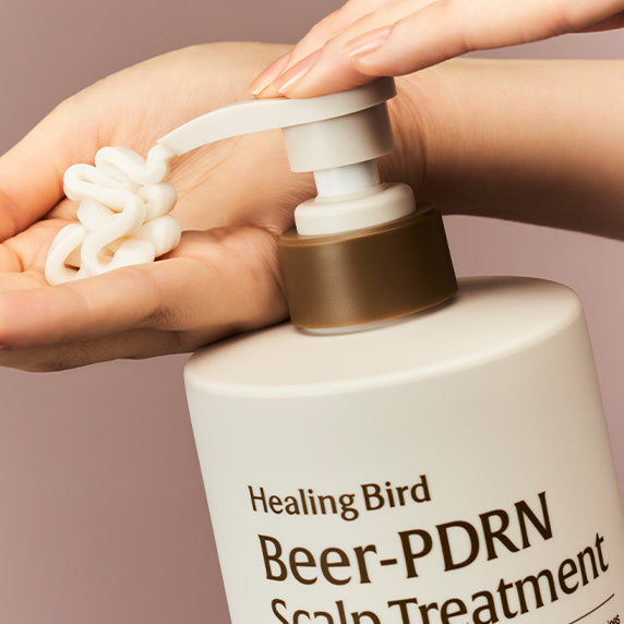 Décris l'image en français: HEALING BIRD Beer PDRN Scalp Treatment 1000ml HealingBird sur mains, mousse sur cuir chevelu