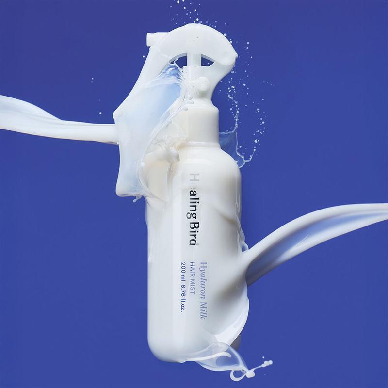 HEALING BIRD Hyalutonic Milk Hair Mist 200ml: bouteille de marque sur fond bleu, brume et éclaboussures blanches.