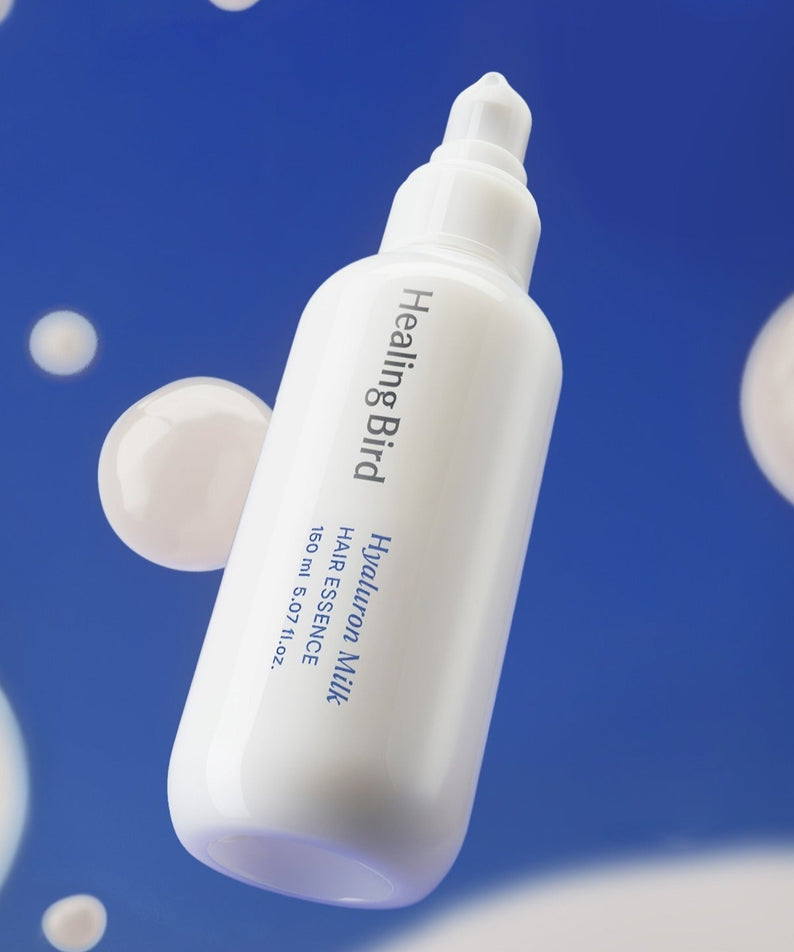 HEALING BIRD Hyaluronic Milk Hair Essence 150ml sur fond bleu avec bulles, soin capillaire hydratant efficace.
