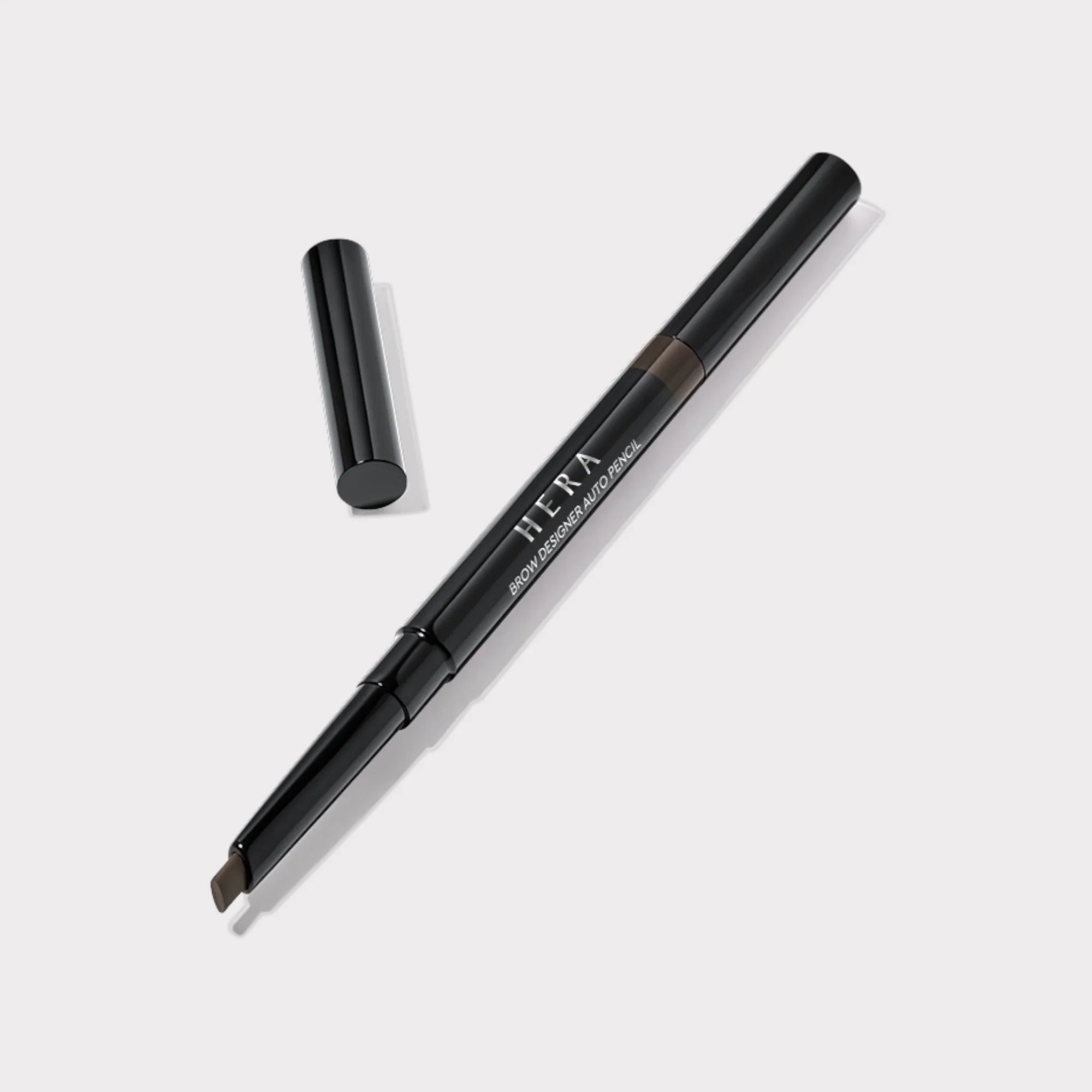 Décris l'image en français : HERA Brow Desighner Auto Pencil, stylo sourcils noir sur fond clair, marque HERA.