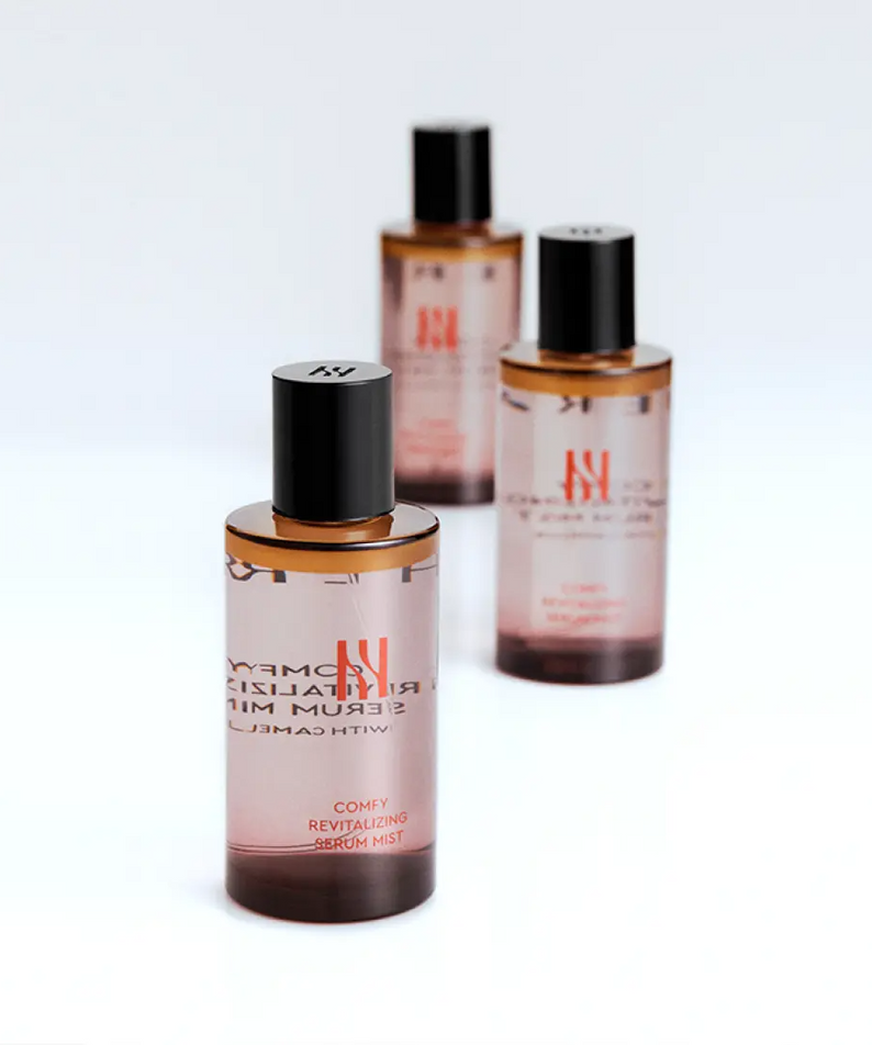 HERA Comfy Revitalizing Serum Mist 90ml de HERA, flacons bruns sur fond blanc, ambiance skincare premium.
