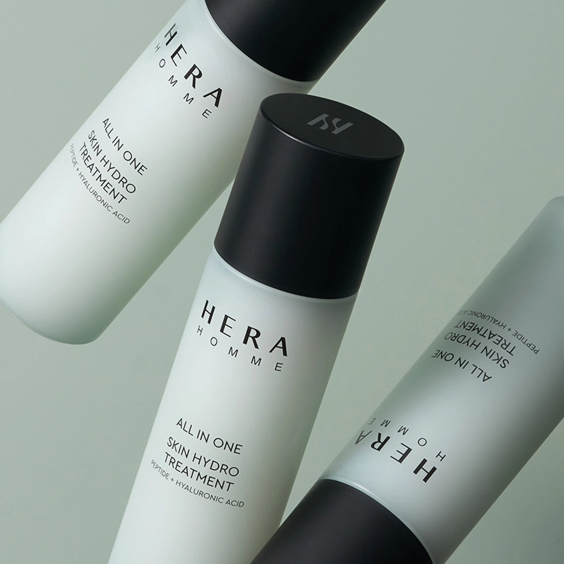 HERA Homme All-in-One Skin Hydro Treatment 150ml de HERA, flacons blancs et noirs sur fond vert clair.