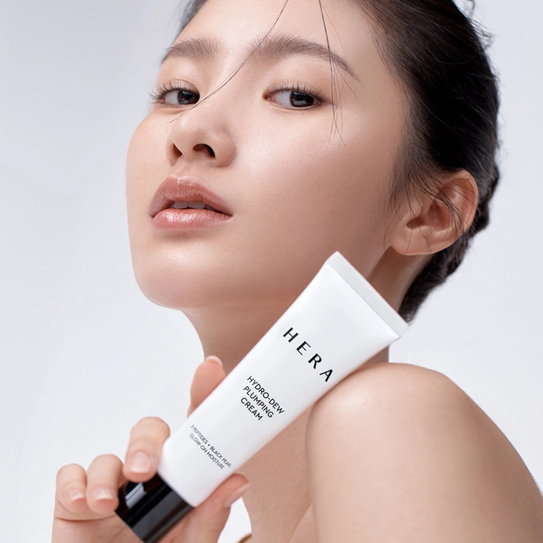 Décris l'image en français en mentionnant HERA Hydro-Dew Plumping Cream 50ml, la marque HERA, sur peau éclatante.