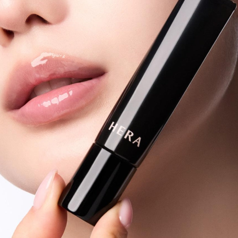 HERA  Lip Serum Intense 11g de HERA, gros plan sur lèvres hydratées tenant le tube noir sur fond clair.