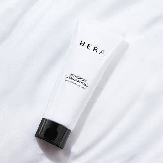 HERA Refreshing Cleansing Foam 160g de la marque HERA, tube blanc sur fond tissu clair, look soin visage.