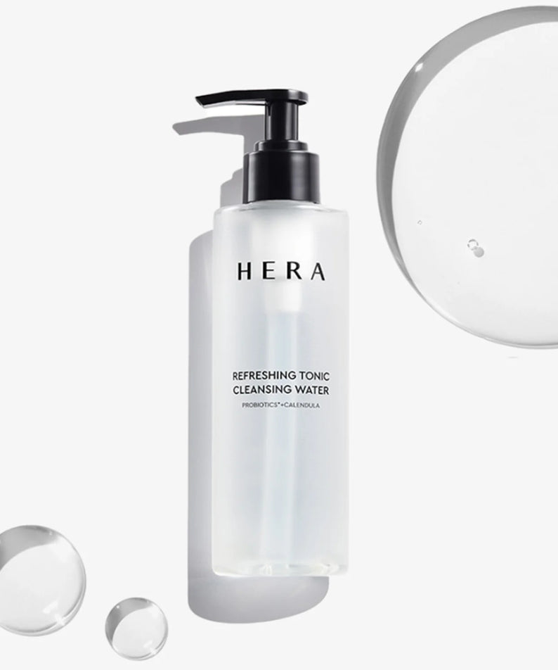 HERA Refreshing Tonic Cleansing Water 200ml, bouteille blanche avec pompe, gouttes et flacons sur fond clair.