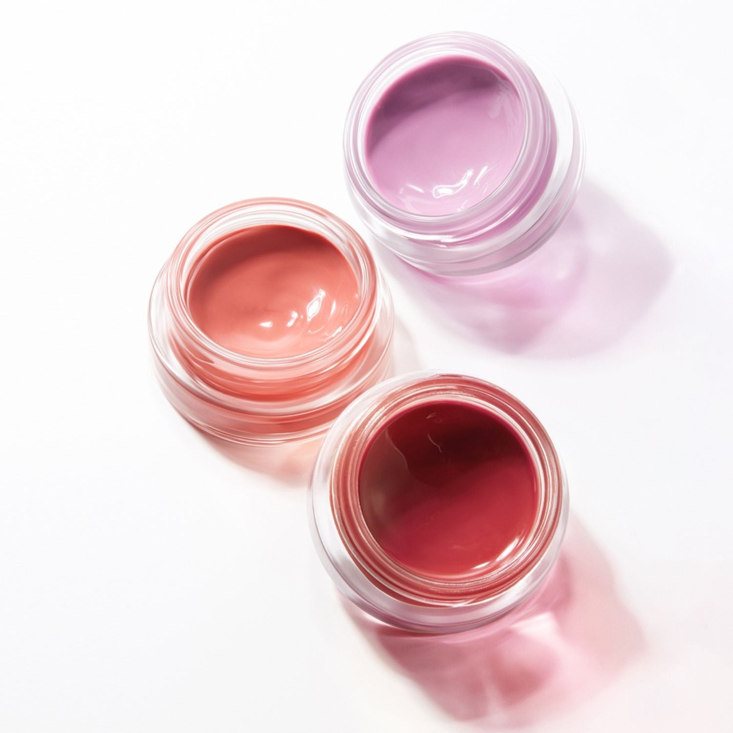 HERA Sensual Lip & Cheek 7g de HERA, pots ouverts de baume lèvres/rouge à joues sur fond clair pastel.