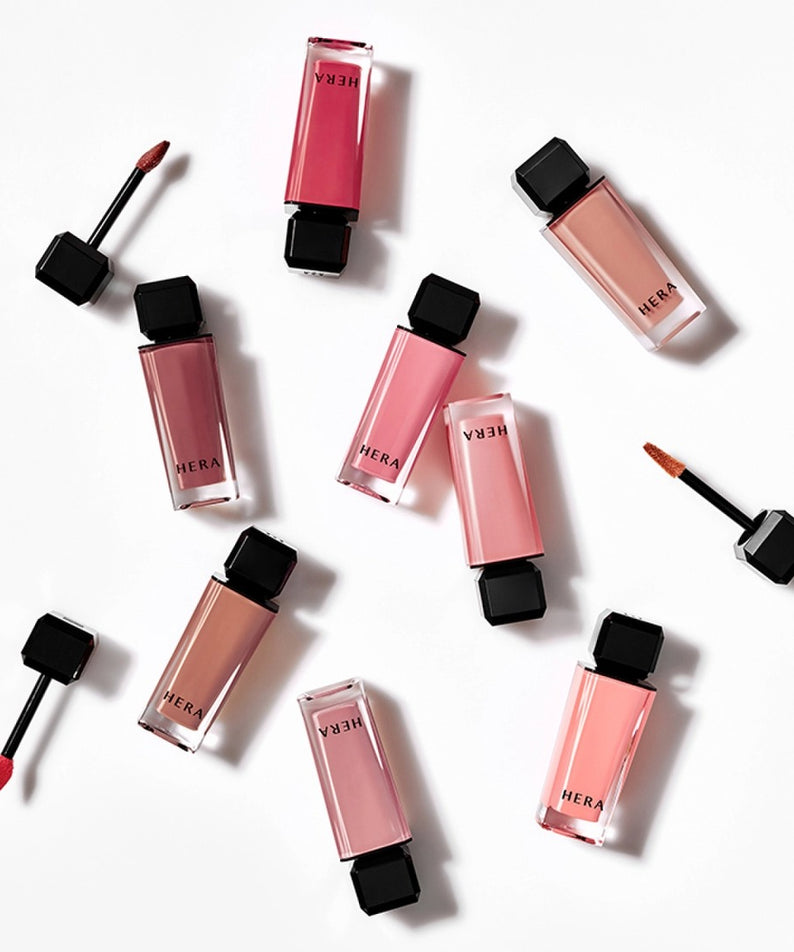 Décris l'image en français: HERA  Sensual Nude Gloss 5g, gloss nude HERA sur fond blanc, vue produit et applicateurs.