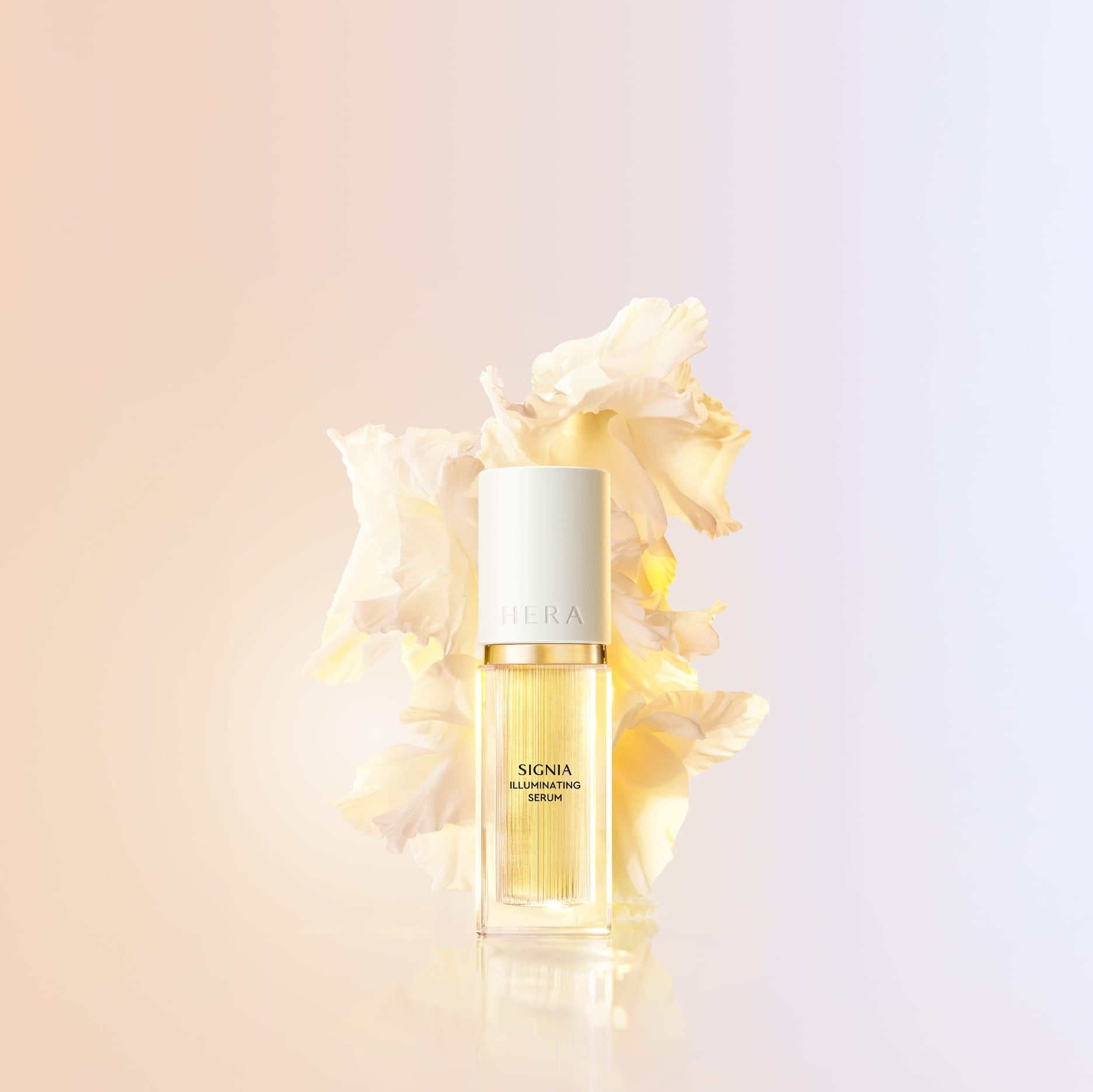 Décris l'image en français : HERA Signia Illuminating Serum 30ml, flacon doré, sur fond clair, fleurs crème en arrière-plan.