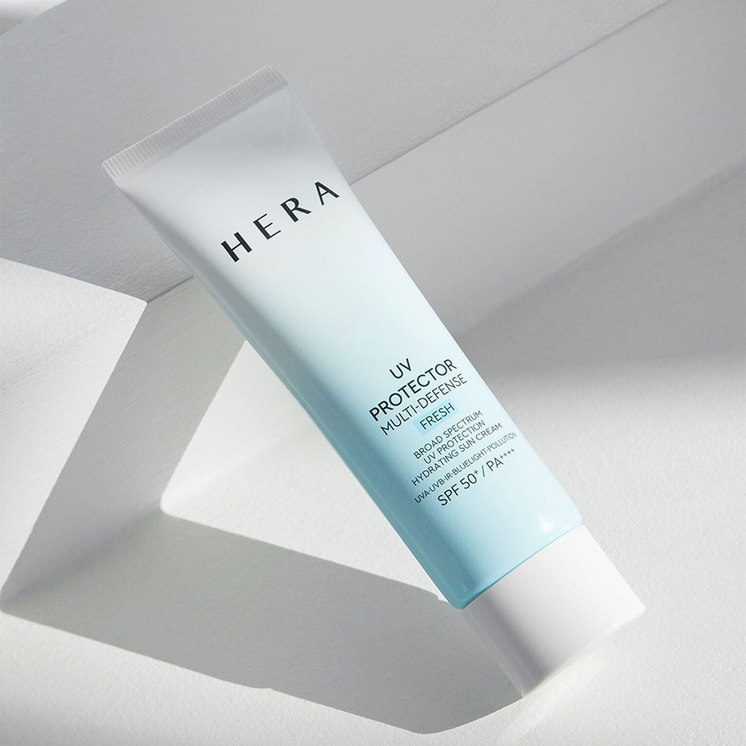 HERA UV Protector Multi-Defense Fresh SPF50+PA++++ 50ml de HERA, tube UV sur fond blanc lumineux, ensoleillé.