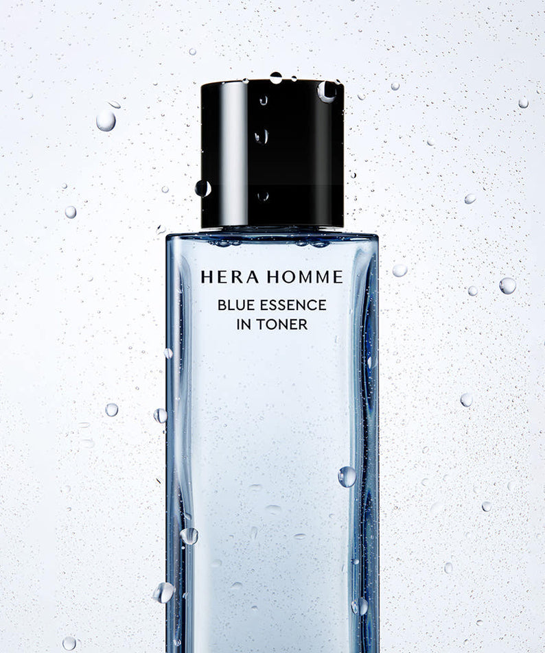 Bouteille de HERA Homme Blue Essence In Toner 125ml sur fond de gouttelettes d'eau