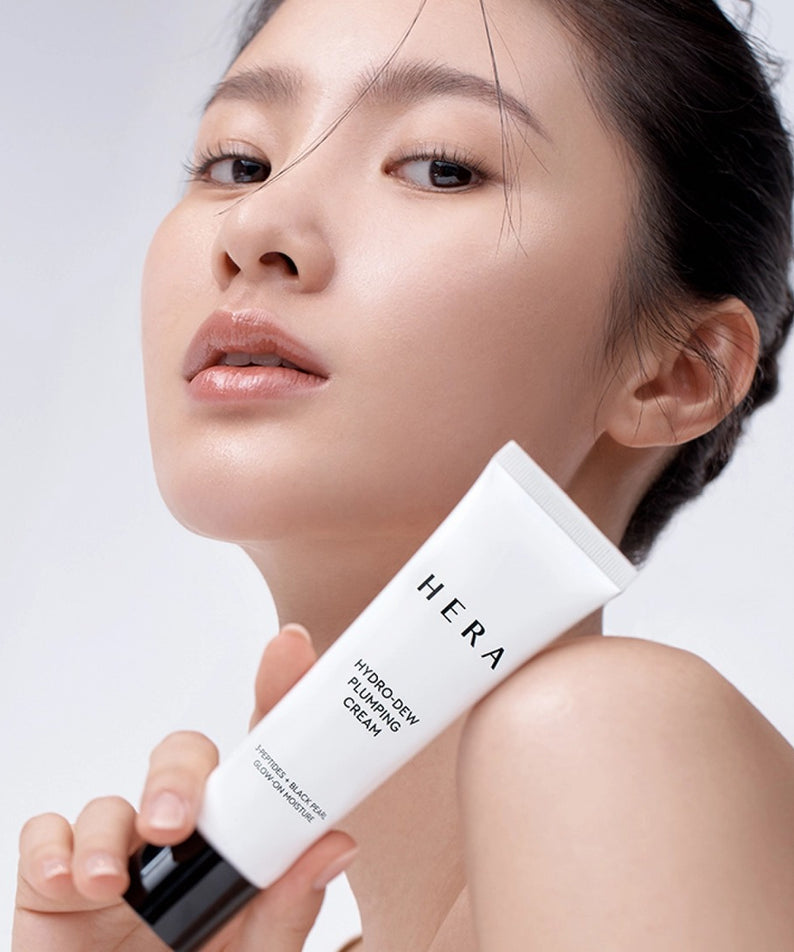 Femme tenant HERA Hydro-Dew Plumping Cream 50ml pour une peau éclatante et hydratée.