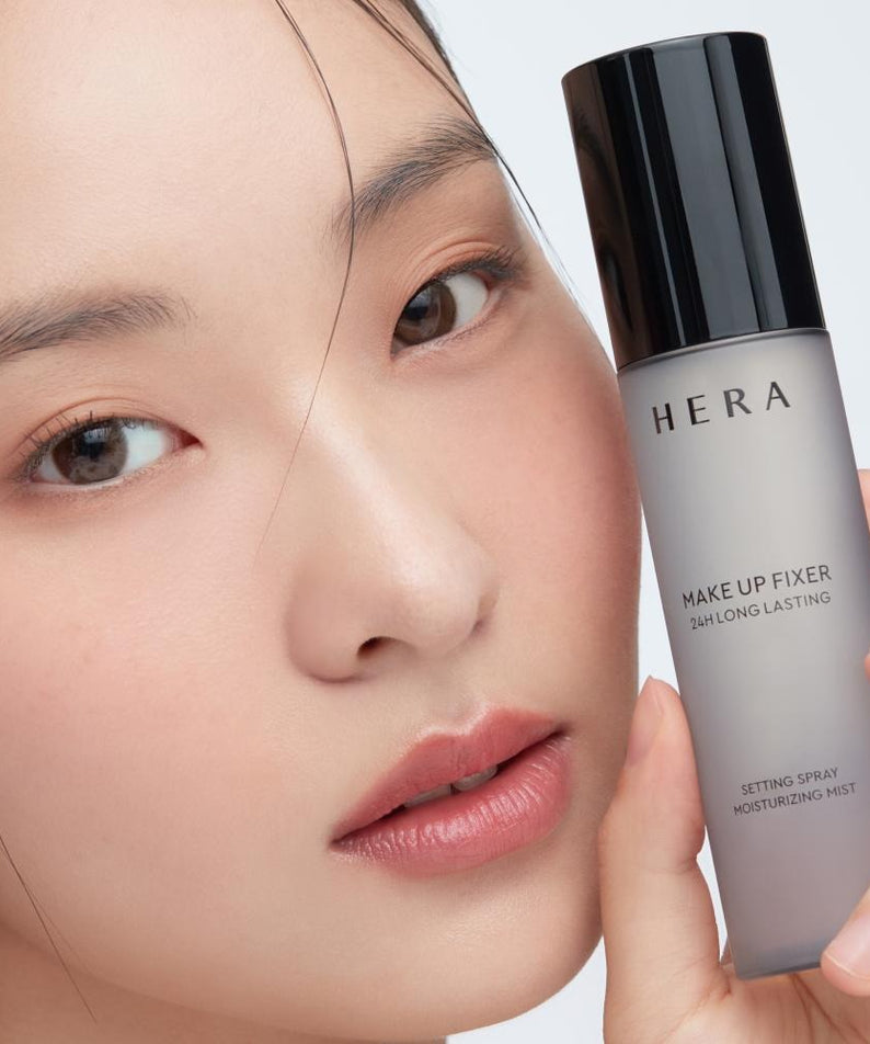 HERA Make Up Fixer 80ml en main par un modèle, spray fixateur de maquillage pour une tenue longue durée et hydratation optimale.