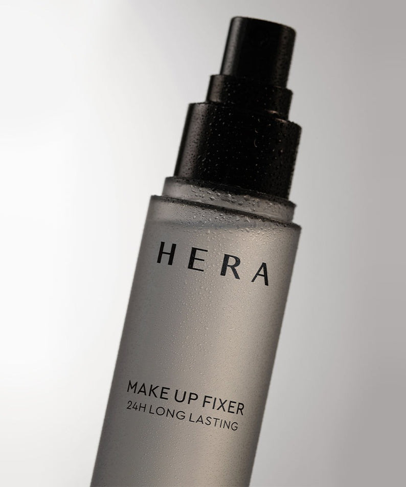 Flacon spray HERA Make Up Fixer 80ml contre fond gris, produit de beauté longue tenue incontournable.
