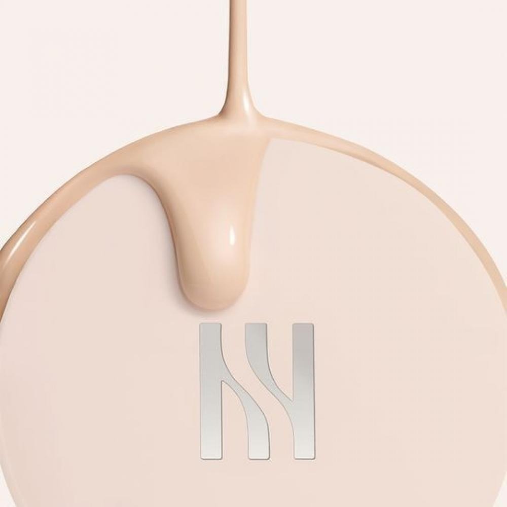 HERA Reflection Skin Glow Cushion Foundation 15g, gros plan du produit HERA sur base beige, texture brillante.