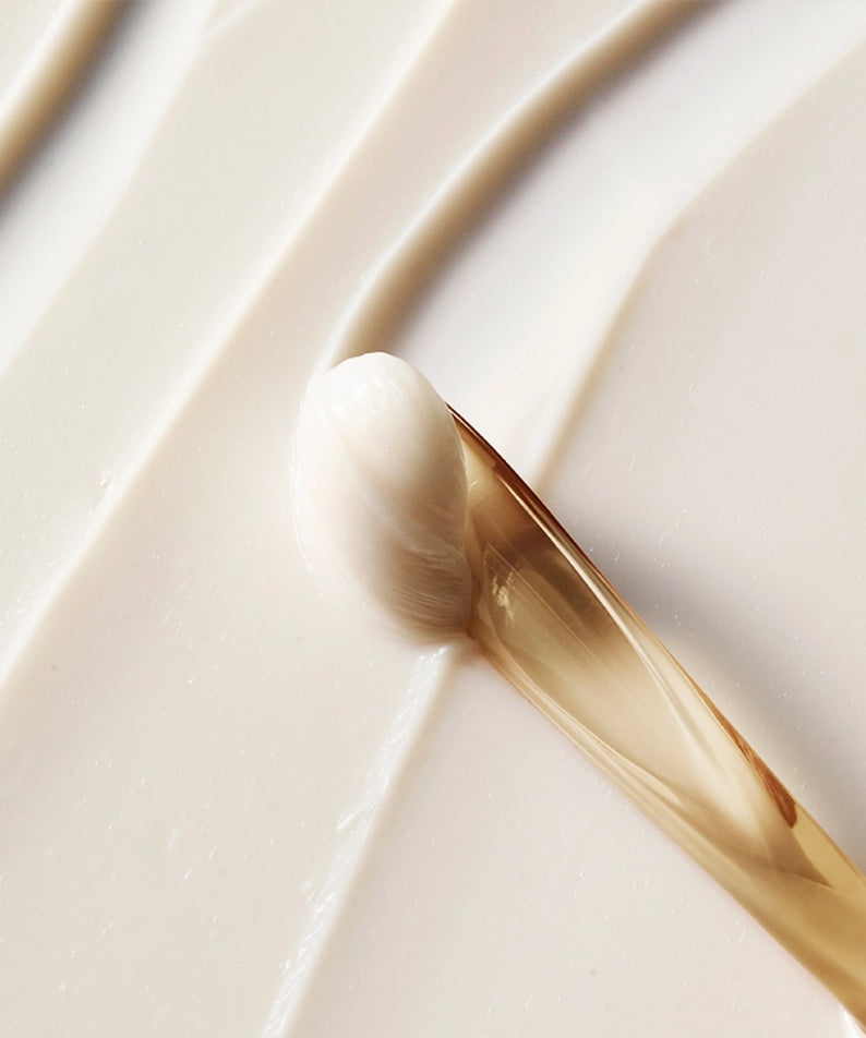 Texture riche de la crème pour les yeux HERA Signa Youth Firming Eye Cream 30ml appliquée avec une spatule dorée.