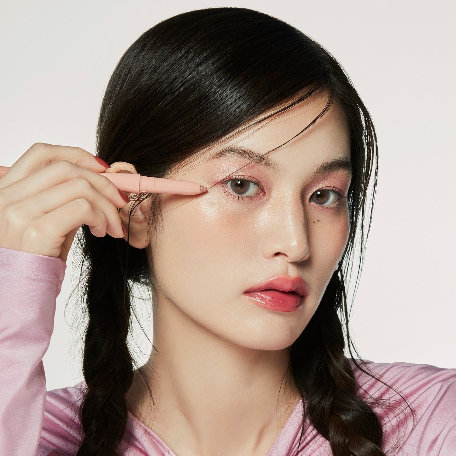 HINCE Depth Dual Color Stick, maquillage en gros plan : une femme applique le stick près de la tempe, fond clair.