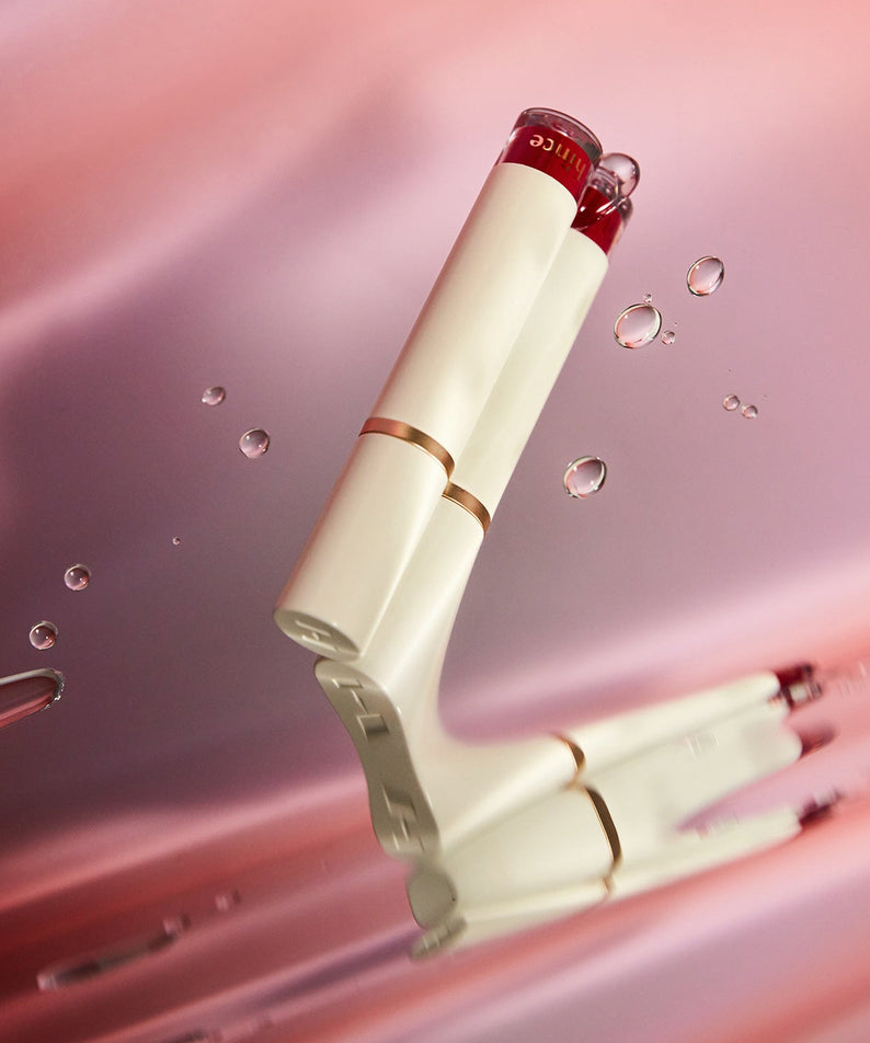 HINCE Mood Enhancer Water Liquid Glow sur fond rose, produit cosmétique élégant et luxueux.