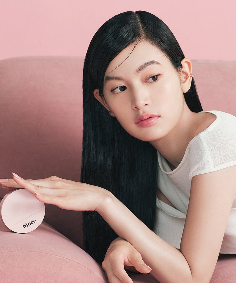 Femme avec le HINCE Cover Master Pink Cushion sur un canapé rose.