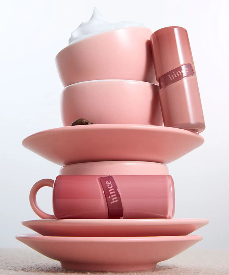 HINCE Low Glow Gel Tint posé sur des tasses roses, évoquant l'élégance et la douceur de ce produit cosmétique unique.