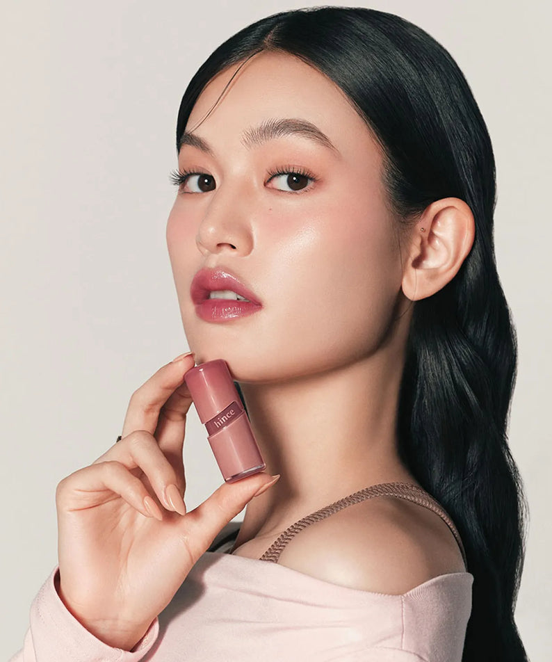 Femme tenant un HINCE Low Glow Gel Tint, maquillage subtil et élégant. Produit cosmétique moderne et chic.