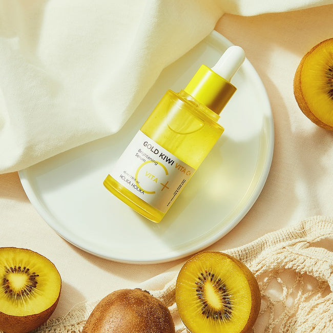 HOLIKA HOLIKA Gold Kiwi Vita C+ Brightening Serum 45ml de Holika, flacon jaune sur assiette avec kiwis.