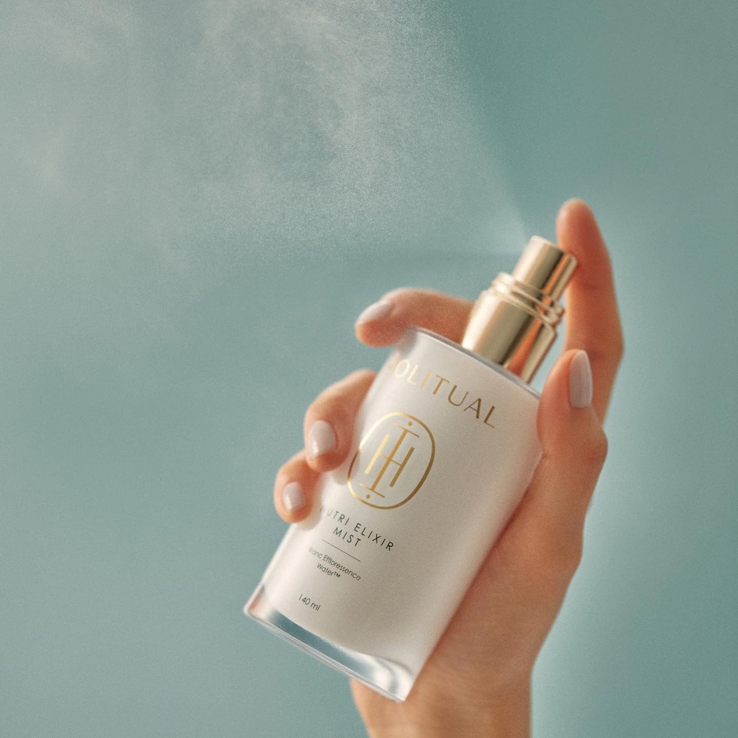 HOLITUAL  Elixir Mist 140ml, brume visage en flacon tenu dans la main sur fond bleu clair