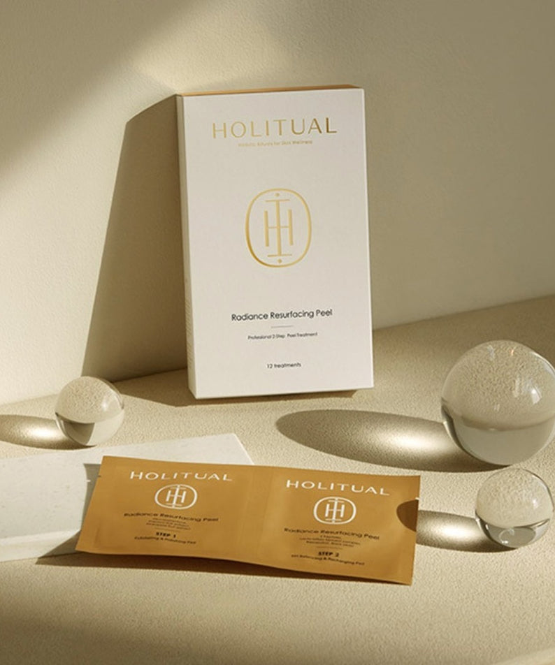 HOLITUAL Radiance Resurfacing Peel de la marque HOLITUAL, coffret et sachets sur table beige, ambiance spa minimaliste.