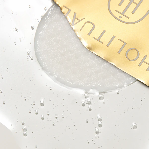 HOLITUAL Radiance Resurfacing Peel de la marque HOLITUAL sur peau en crème grise, fond blanc perles de beauté.