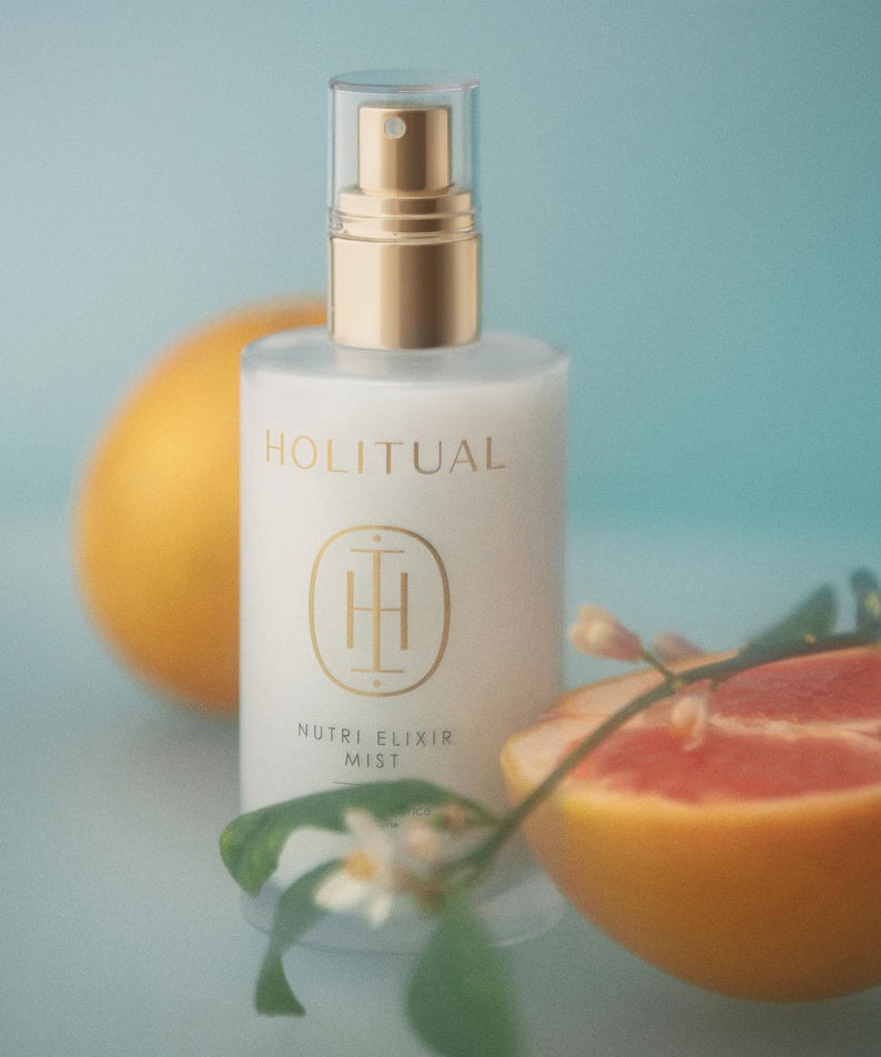 HOLITUAL Elixir Mist 140ml en flacon vaporisateur sur fond de pamplemousse, produit de beauté hydratant et rafraîchissant.