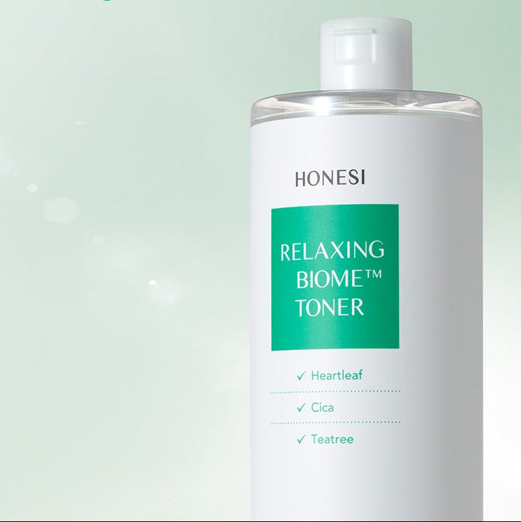 Décris l'image en français : HONESI  Relaxing Biome Toner 500ml, flacon blanc, arrière-plan vert apaisant.