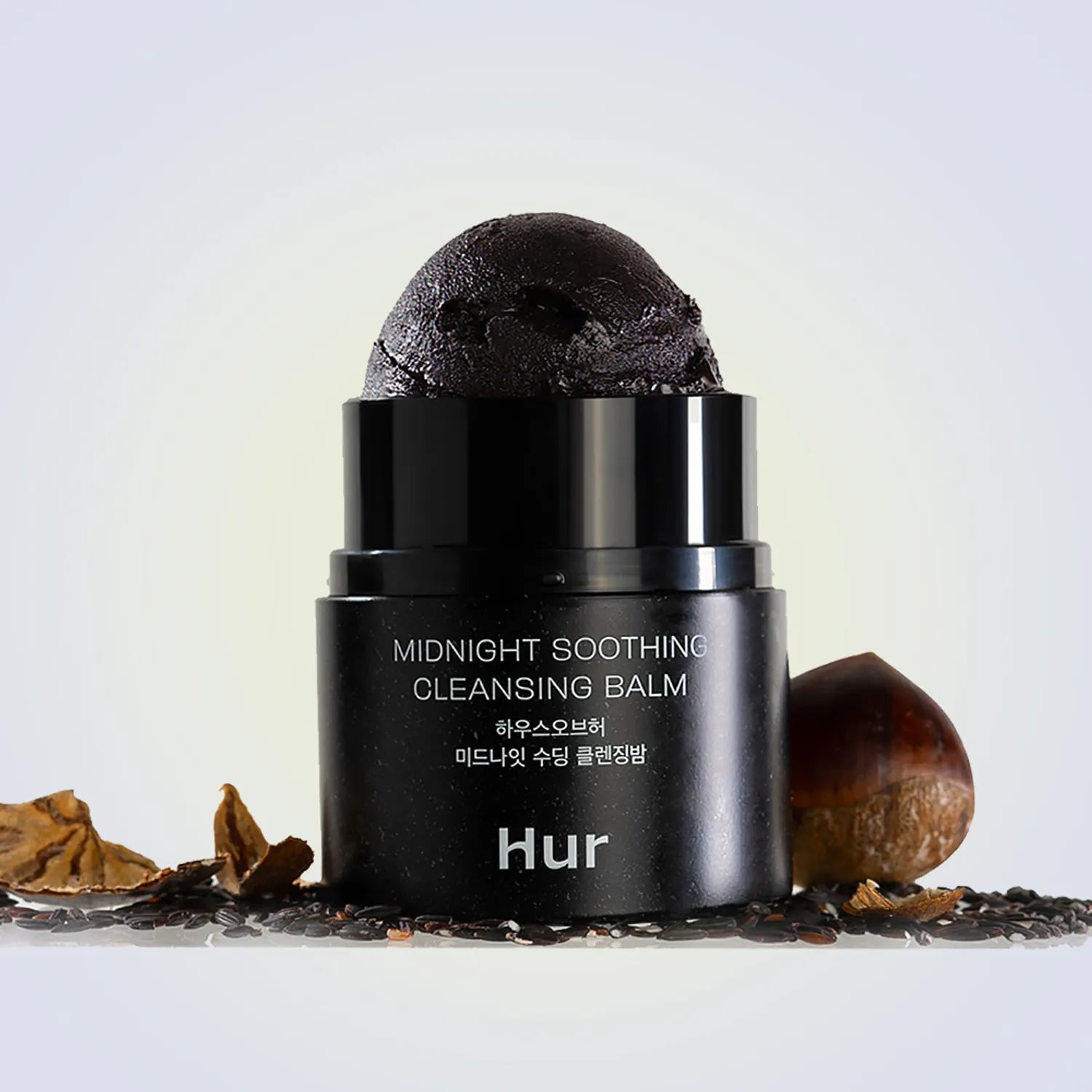 HOUSE OF HUR Midnight Soothing Cleansing Balm : baume noir « HUR » sur fond clair avec pierres et éléments naturels