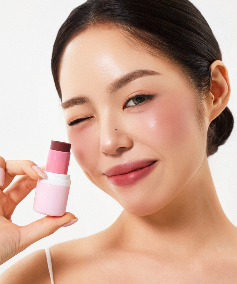 Femme souriante appliquant le blush HOUSE OF HUR Every Cheek Blush pour un teint éclatant et naturel.