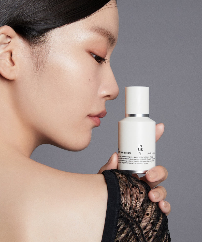 Femme tenant un flacon de HUXLEY Biosys 360 Cream, soin du visage haut de gamme pour une peau éclatante.