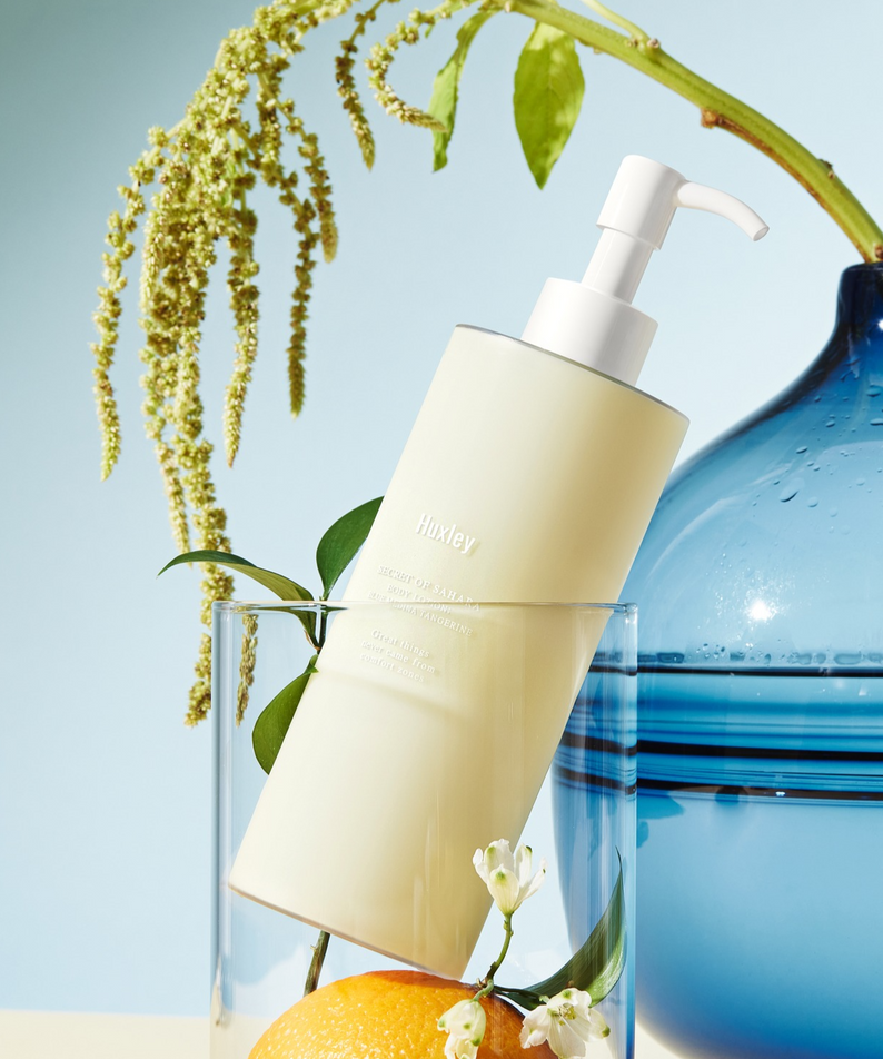 HUXLEY Body Lotion Blue Madina Tangerine avec des notes de mandarine et un design élégant, posé devant un fond bleu.