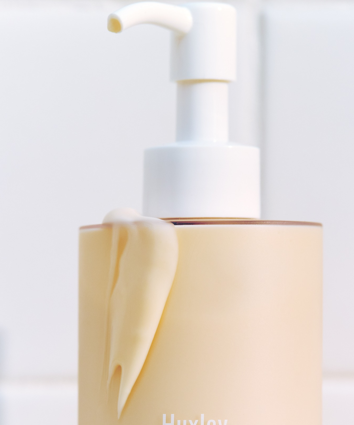 Flacon de HUXLEY Body Lotion Blue Madina Tangerine sur fond blanc, pompe distributrice visible, texture de lotion douce et crémeuse.