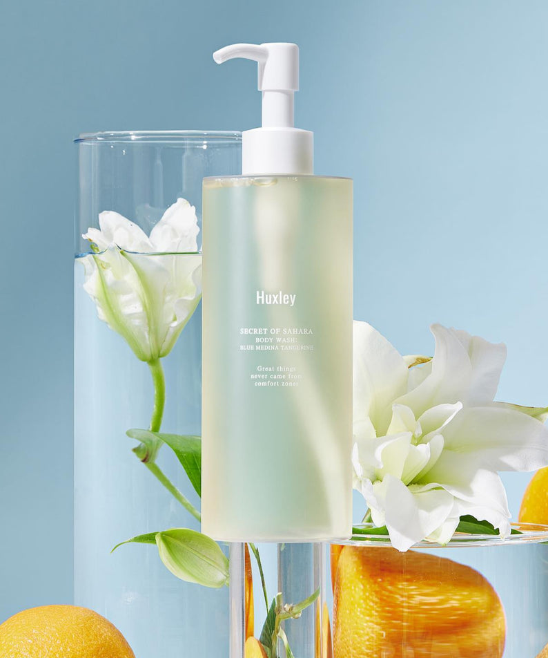 HUXLEY Body Wash Blue Medina Tangerine avec décor élégant de fleurs et agrumes, flacon pompe sur fond bleu.