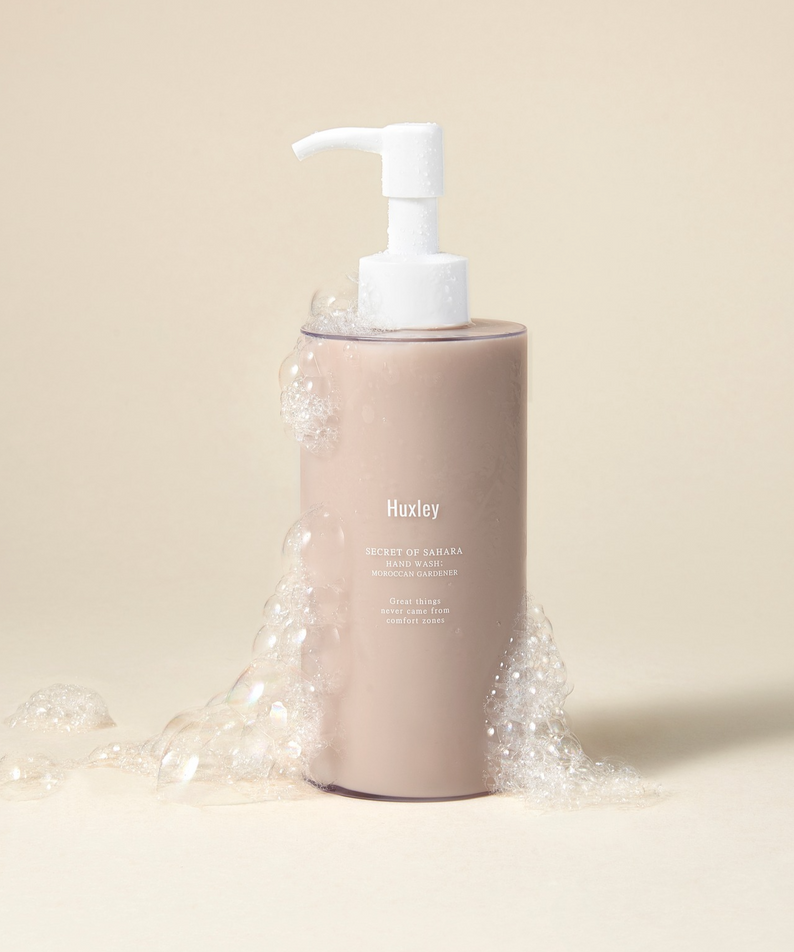 Savon pour les mains HUXLEY Hand Wash Moroccan Gardener dans une bouteille avec mousse, fond beige.