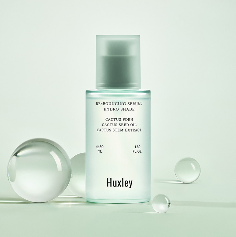 Décris l'image en français : HUXLEY Rebouncing Serum Hydro Shade 50ml de la marque Huxley, flacon sur fond vert clair.